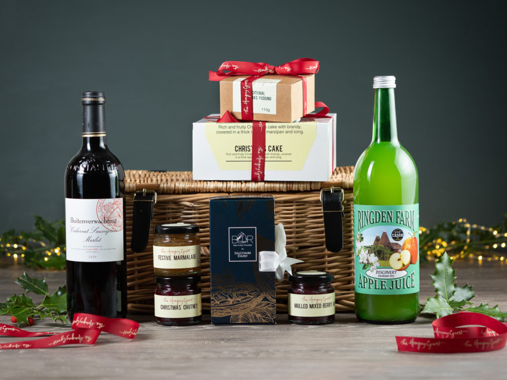 Wicker hamper filled with Festive Marmalade, Christmas chutney, Nulled berry jam, Christmas cake and pudding, Ringden apple juice, Salcombe dairy chocolate bar library, and a choice of bottle of red or white wine. perfect Christmas gift