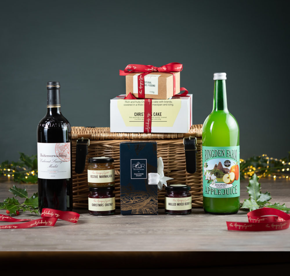 Wicker hamper filled with Festive Marmalade, Christmas chutney, Nulled berry jam, Christmas cake and pudding, Ringden apple juice, Salcombe dairy chocolate bar library, and a choice of bottle of red or white wine. perfect Christmas gift