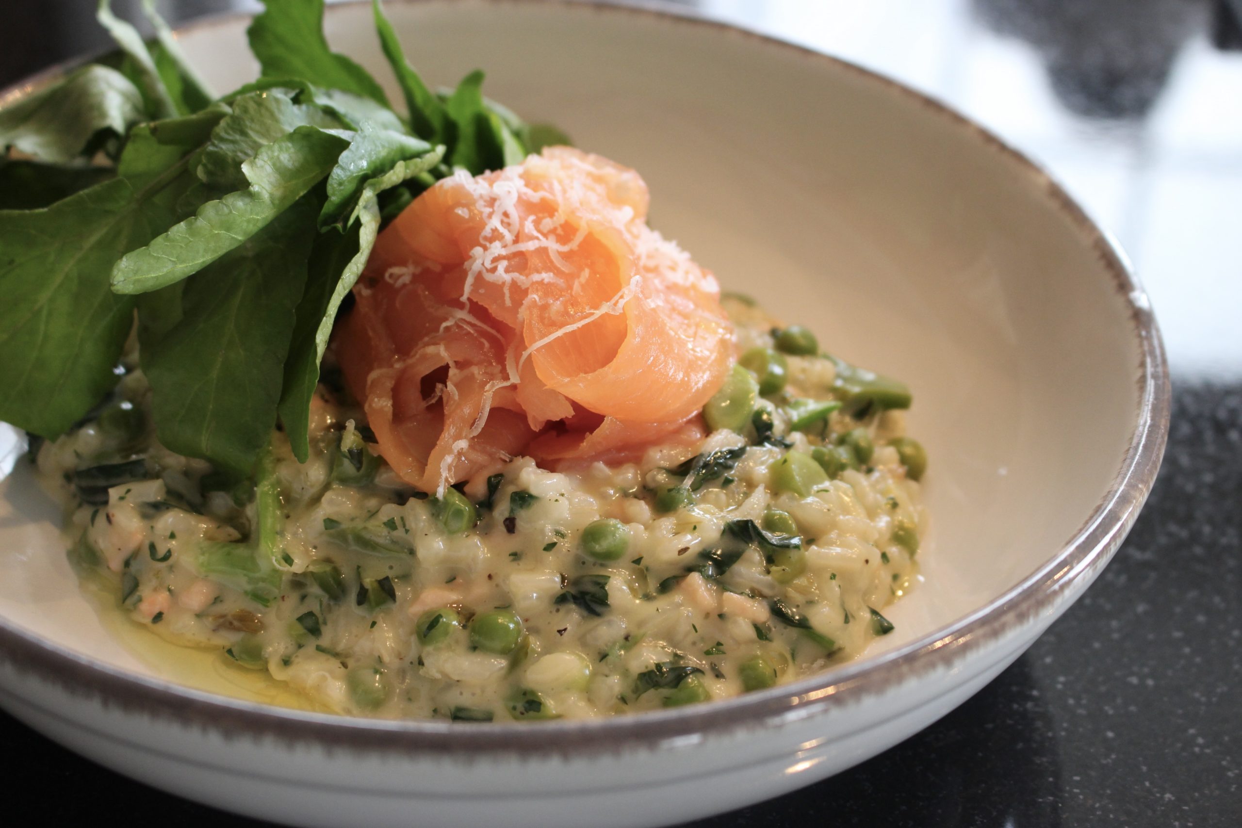 A bowl of wild garlic and spring green risotto with chopped smoked salmon